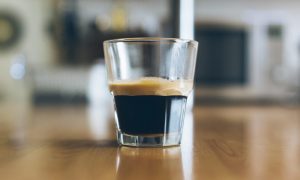 Expreso en vaso de cristal sobre mesa de madera